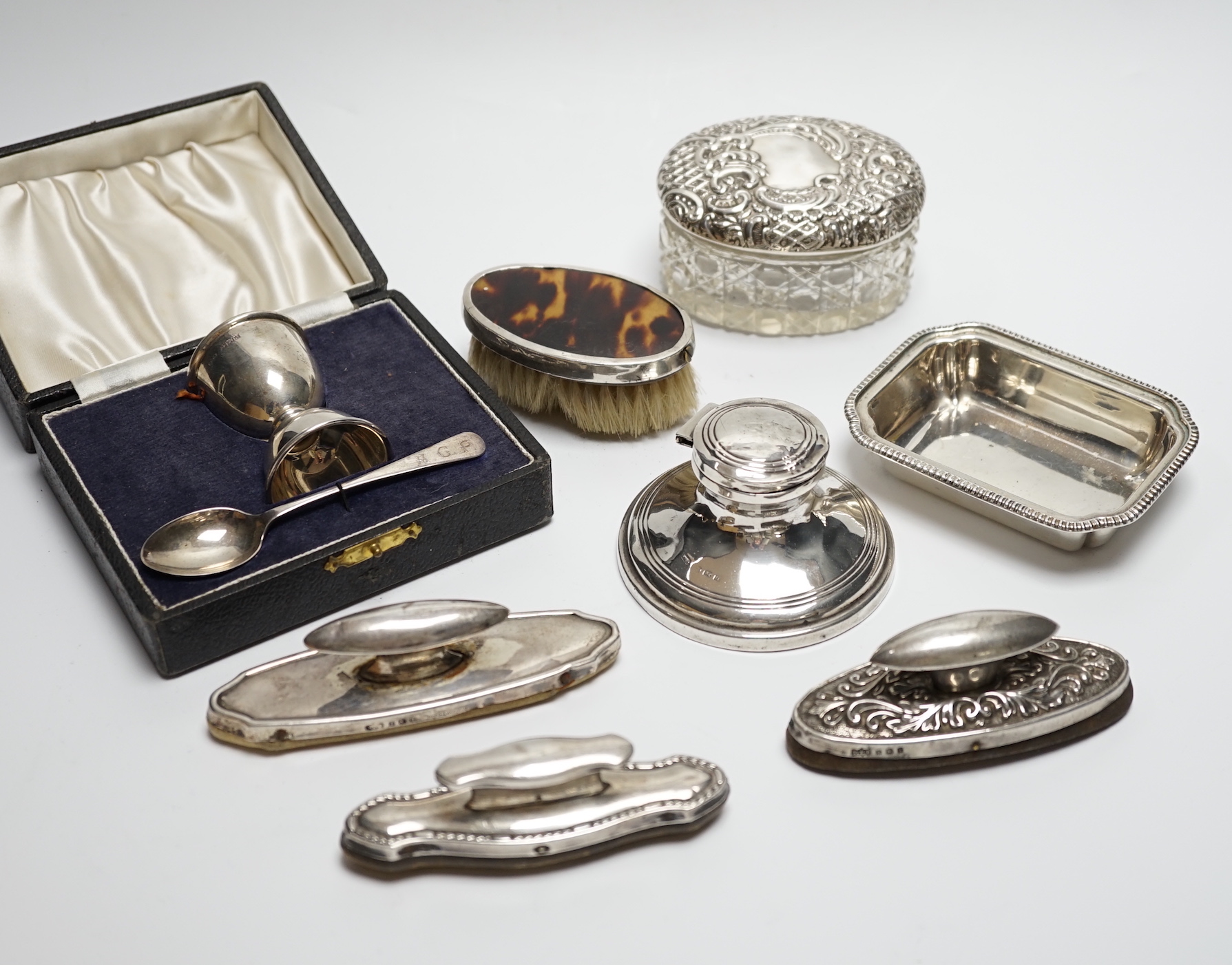 A cased silver christening egg cup and spoons and other items including nail buffers, inkwell, brushes etc.